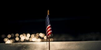 Close-up of a small American flag on a reflective surface with the word PENTAGON in the background