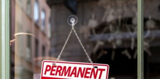 A sign reading 'PERMANENT CLOSURE' hanging in a shop window