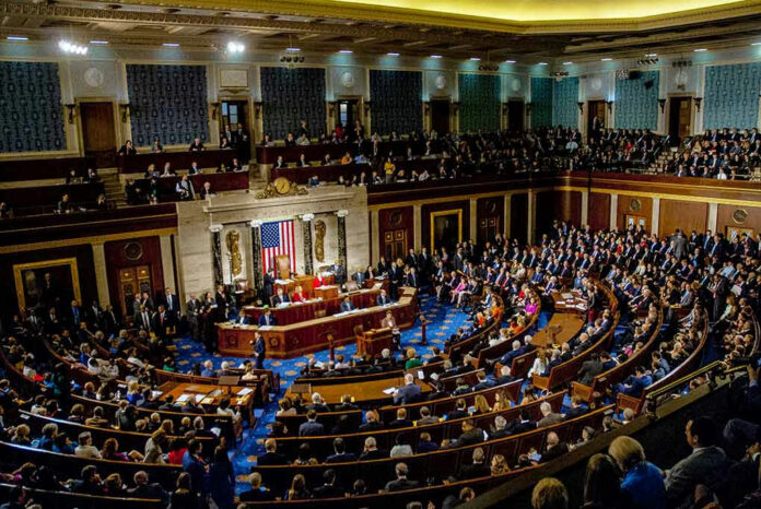 1186368262 Crowded legislative chamber with people seated and standing.