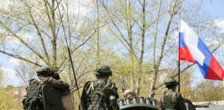 Soldiers on an armored vehicle with a national flag