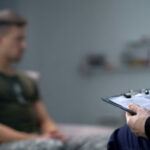 Therapist taking notes while talking with a young man.