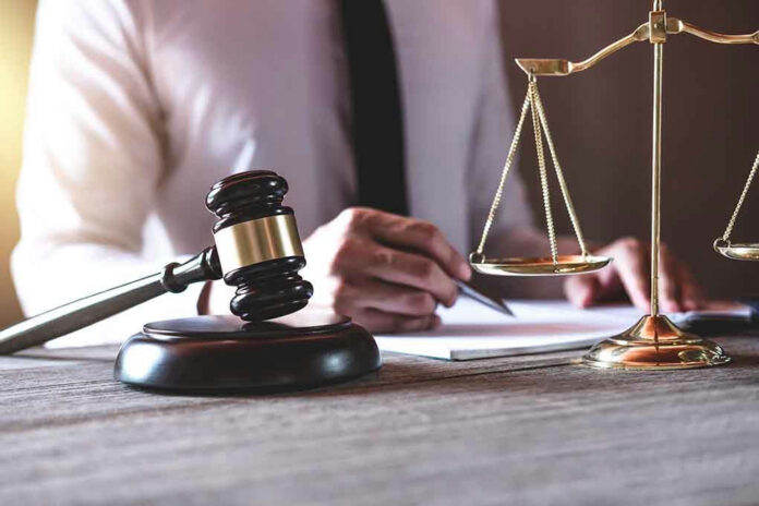 1177368778 Gavel and scales beside a person writing.