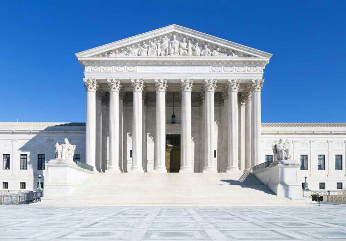 White columned building with stairs under a blue sky.
