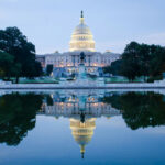 United States Capitol building reflected in a calm pool at dusk