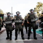 Sheriff deputies in riot gear standing in formation during a protest