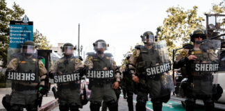 Sheriff deputies in riot gear standing in formation during a protest