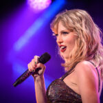 Private Awards Gala Raises Access Questions Singer performing on stage with a microphone under colorful lights