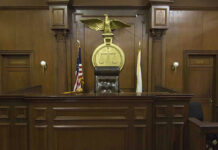 Police Say Snapchat Video Captured Child Sexual Assault Judges bench in an empty courtroom, scales emblem above.