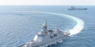 Warships maneuvering at sea, leaving a white wake.