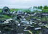 Three Killed After Twin-Engine Plane Crashes Wreckage of crashed plane scattered across field, smoke rising.