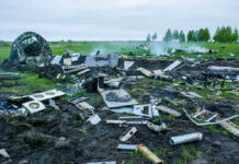 Three Killed After Twin-Engine Plane Crashes Wreckage of crashed plane scattered across field, smoke rising.