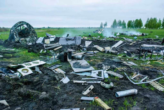 1398181061 Wreckage of crashed plane scattered across field, smoke rising.