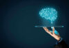 Digital brain above a hand holding a tablet.