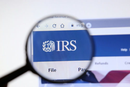 Magnifying glass over IRS website logo.