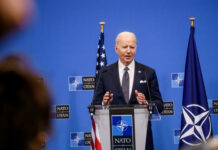 Europe Opens Its Wallet, But NATO Wants More Than Cash man in suit speaking at a podium with NATO backdrop