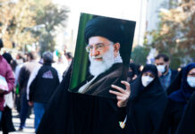 Person holding a large portrait in a crowd