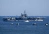 Aircraft carrier at sea with small boat alongside