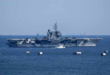 Gas Prices Hijacked By Red Sea Rebels Aircraft carrier at sea with small boat alongside