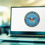 Laptop displaying Department of Defense logo on the screen.
