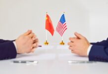 China Locks the Exits—Deals Get Unwound Two hands of individuals facing each other with flags of China and the USA on the table