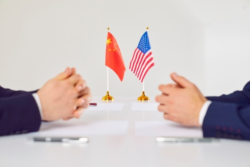 Flags,Of,America,And,China,Atand,On,Table,During,Talks Two hands of individuals facing each other with flags of China and the USA on the table