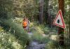 How Two Teen Girls Escaped an Alleged Knife Attack in the Woods Two hikers on a forest trail near a warning sign about ticks