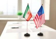 Sanctions Dispute Fuels New Questions About U.S Mini flags of Iran and the United States on a conference table