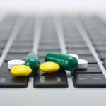 Pills scattered on a laptop keyboard.