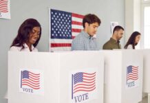 People voting in booths with American flags.