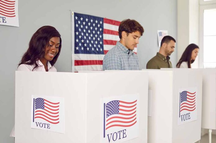 People voting in booths with American flags.