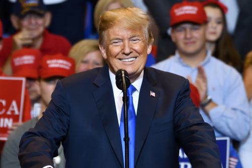 A man speaking at rally with supporters in background.