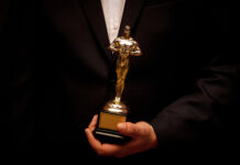 Person holding an Oscar statuette in formal attire.