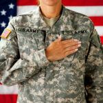 Soldier saluting in front of an American flag.