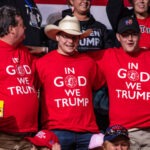 Three men wearing "In God We Trump" shirts.