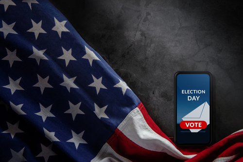 U.S. flag and phone displaying "Election Day" voting message.