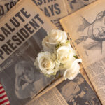 Newspapers, roses, and American flag mourning John F. Kennedy.