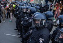 Riot police officers in line during a public protest.