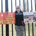 Protester holding fentanyl awareness signs outside White House fence.