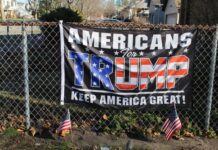 Americans for Trump banner on a fence with flags