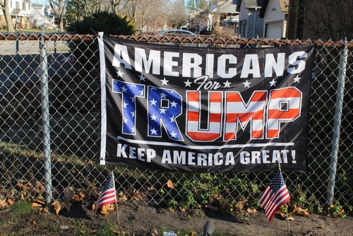 Americans for Trump banner on a fence with flags