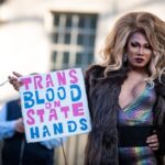 Person holding sign reading "Trans Blood on State Hands."