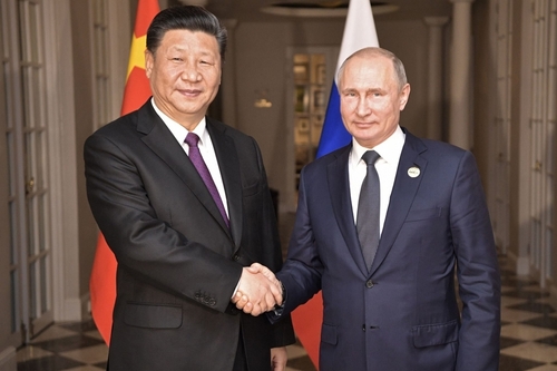 Xi Jinping and Vladimir Putin shaking hands indoors.