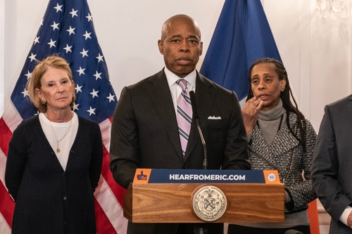 People standing at a podium with flags behind them.