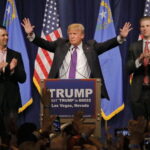 Donald Trump at a rally with his sons applauding.