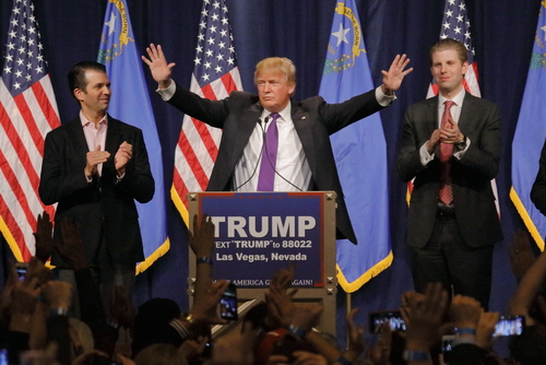 Donald Trump at a rally with his sons applauding.